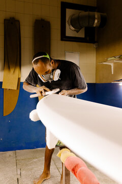 Artisan operating a hand sanding tool to shape a freshly built board