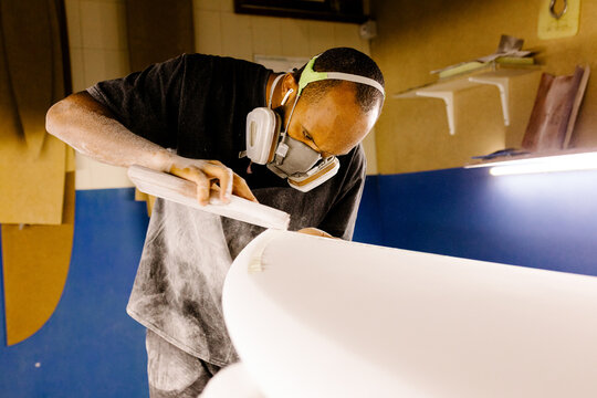 Surfboard craftsman using a hand-held sanding tool