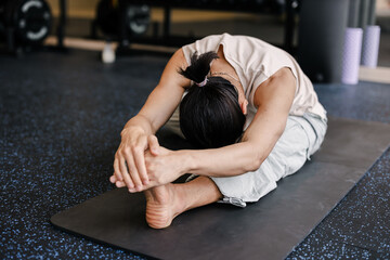 Person Doing Hamstring Stretch On Yoga Mat In Gym