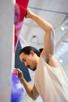 Climber Reaching for Red Hold in Indoor Rock Gym Training Session