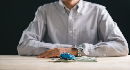 Car loan and auto finance planning, person considering buying new vehicle, miniature automobile on money stack, saving cash for purchase cost, thinking about bank loan or insurance policy