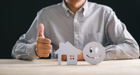 Home customer satisfaction review concept, person shows thumbs up near house shape and smiley face, symbolizing best real estate property feedback and service five star rating