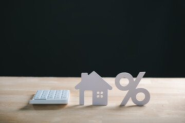 Home property real estate mortgage interest rate percent calculation shown with house model percentage sign and calculator on wood desk for financial planning