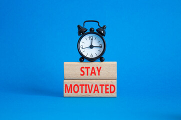 Motivation symbol. Concept words Stay Motivated on wooden blocks. Beautiful blue background with alarm clock. Business and Stay Motivated concept. Copy space