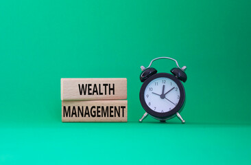 Wealth Management symbol. Concept words Wealth Management on wooden blocks. Beautiful green background with alarm clock. Business and Wealth Management concept. Copy space