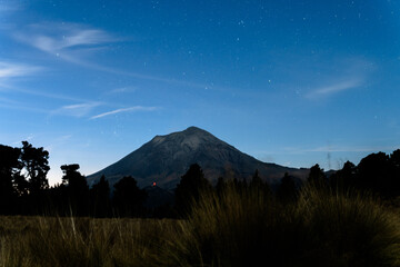 Popocatepetl volcano glowing red under starry night sky