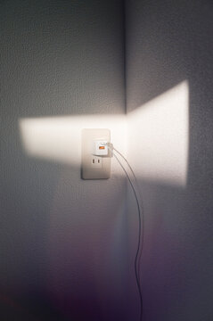 Plugged in charger with sunlight on wall
