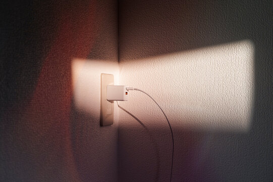 Plugged in charger with sunlight on wall
