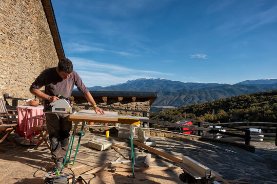 Woodworker working outside, a rural house