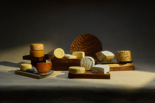A still-life of assorted cheeses arranged on wooden platters
