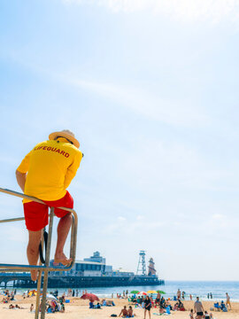 Lifeguard Observes Busy Beach on a Sunny Day Near a Pier