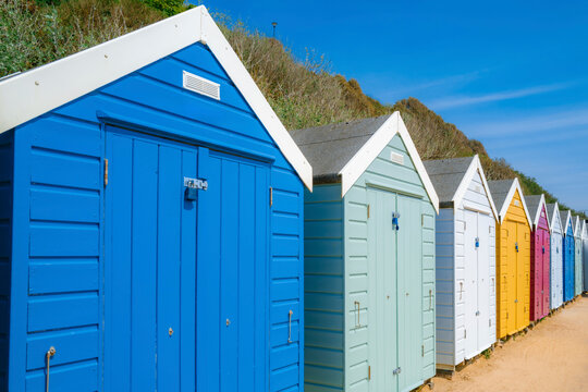 Colourful Beach Boxes Line the Sandy Shore Under a Clear Blue Sky