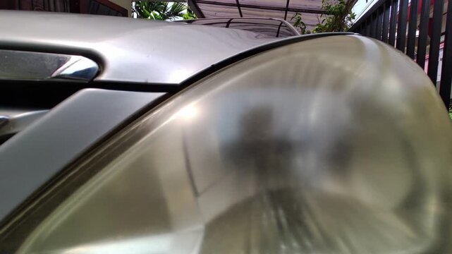Close-up of a faded and cloudy car headlight showing signs of aging, oxidation, and wear. Represents vehicle maintenance, automotive repair, safety issues, and used car condition.