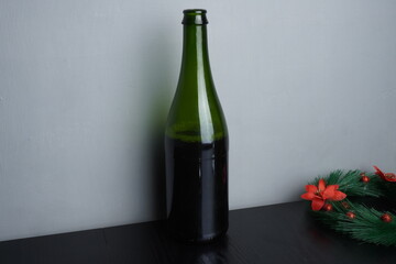 Wine bottle and glass on black wooden table as Christmas festive holiday decoration. Blank background mockup with copy space for adding text, logo, product, or promotional design.