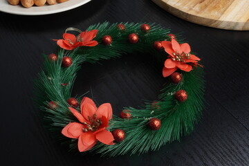 Christmas gift boxes with red and green ribbon, wreath garland, candy cane, santa sock, bauble and golden bells on black wooden table. Blank background mockup with copy space for adding text