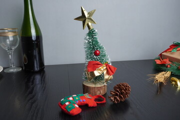 Christmas gift boxes with red and green ribbon, wreath garland, candy cane, santa sock, bauble on black wooden table with festive holiday decoration and some traditional food. Blank background mockup 