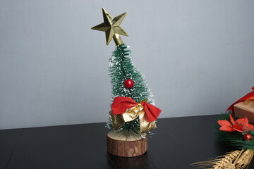 Christmas gift boxes with red and green ribbon, wreath garland, candy cane, santa sock, bauble and golden bells on black wooden table. Blank background mockup with copy space for adding text