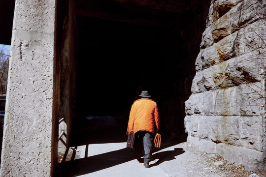 A man on carries suitcases through a dark underpass 