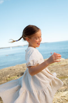 Candid joy by the shore as a girl spins in a white dress