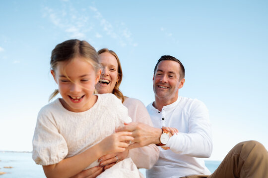 Candid family moment at the beach with smiling parents and daugh