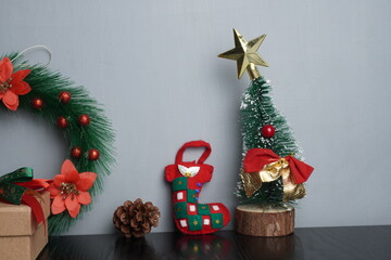 Christmas gift boxes with red and green ribbon, wreath garland, candy cane, santa sock, bauble on black wooden table with festive holiday decoration and some traditional food. Blank background mockup 