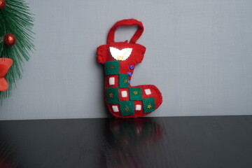 Christmas gift boxes with red and green ribbon, wreath garland, candy cane, santa sock, bauble and golden bells on black wooden table. Blank background mockup with copy space for adding text