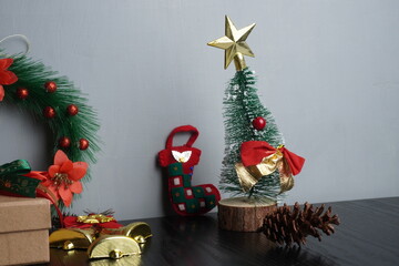 Christmas gift boxes with red and green ribbon, wreath garland, candy cane, santa sock, bauble on black wooden table with festive holiday decoration and some traditional food. Blank background mockup 