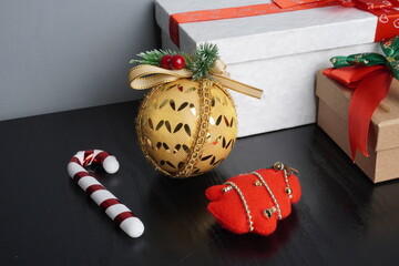 Christmas gift boxes with red and green ribbon, wreath garland, candy cane, santa sock, bauble on black wooden table with festive holiday decoration and some traditional food. Blank background mockup 