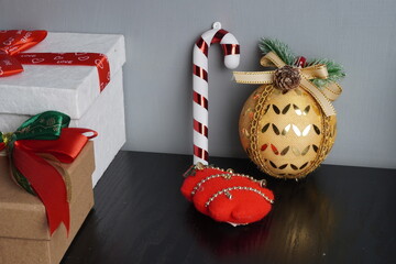 Christmas gift boxes with red and green ribbon, wreath garland, candy cane, santa sock, bauble on black wooden table with festive holiday decoration and some traditional food. Blank background mockup 