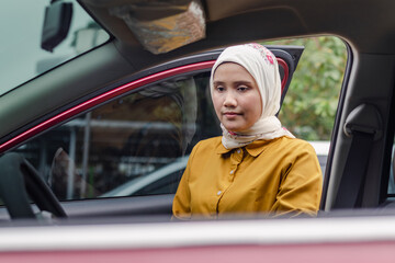 A young Indonesian Muslim woman getting into a car to driving her car
