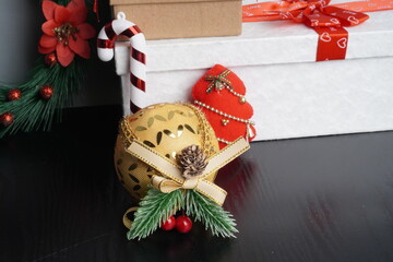 Christmas gift boxes with red and green ribbon, wreath garland, candy cane, santa sock, bauble on black wooden table with festive holiday decoration and some traditional food. Blank background mockup 
