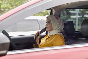 A young Indonesian Muslim woman fastening her seat belt