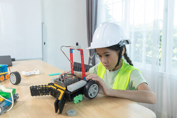 Focused young girl wearing hard hat and safety vest building a robotic vehicle, symbolizing STEM education, innovation and hands on learning in engineering and technology for kids.