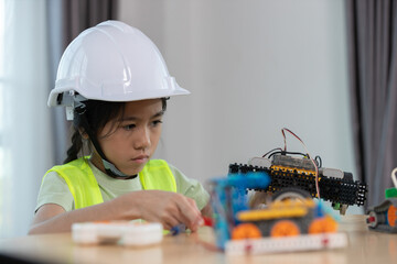 Focused young girl wearing hard hat and safety vest building a robotic vehicle, symbolizing STEM education, innovation and hands on learning in engineering and technology for kids.