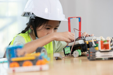 Focused young girl wearing hard hat and safety vest building a robotic vehicle, symbolizing STEM education, innovation and hands on learning in engineering and technology for kids.