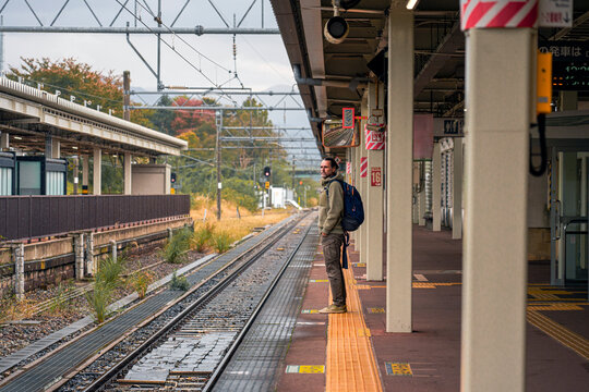 Man with backpack waiting at train station platform in Japan