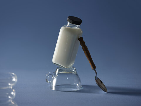 Milk bottle balanced on a teacup with a spoon