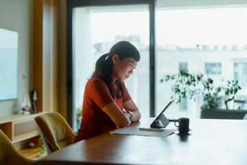 Asian woman working focused with tablet at home
