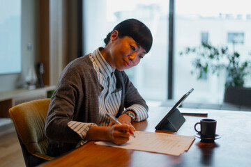 Asian businesswoman signing contract documentation at home office desk