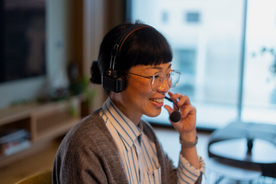 Asian woman working from home using headset
