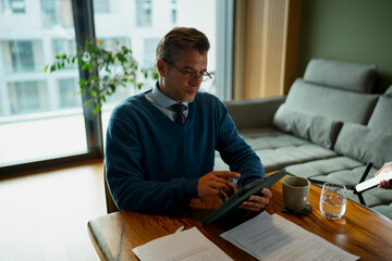 Businessman working from home using tablet and documents

