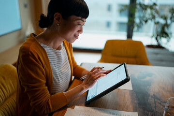 Asian woman working on digital tablet with stylus
