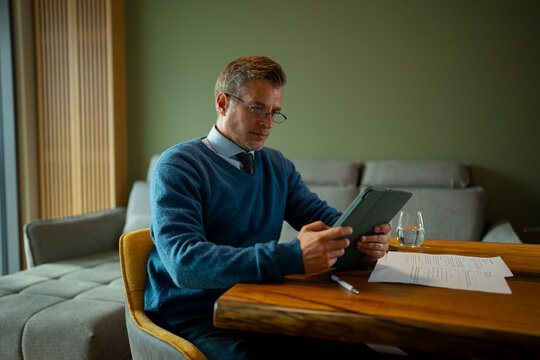 Mature businessman working remotely on tablet from home
