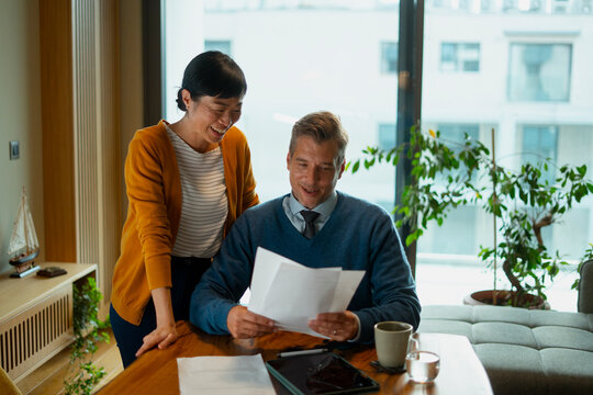 Mature diverse couple happily managing home finances paperwork
