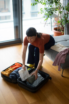 Woman packing suitcase with clothes for upcoming journey
