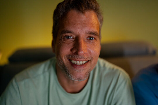 Man smiling engaging the camera feeling contented indoors
