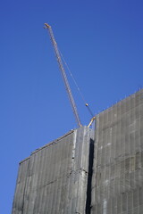Large yellow construction crane and building under construction with blue sky and copy space
