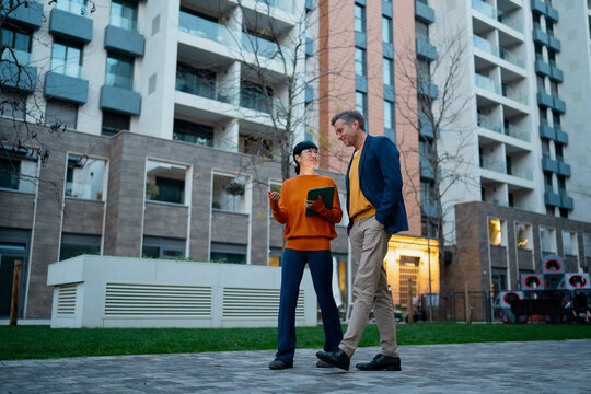 Real estate agent showing client residential property outdoors
