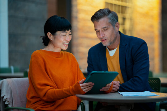 Colleagues collaborating on tablet discussing business outdoors
