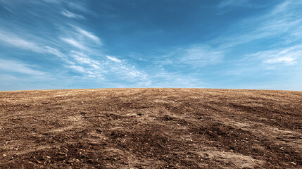 A vast expanse of barren land stretches out beneath a vibrant, cloud-strewn sky, creating a sense of isolation and desolation